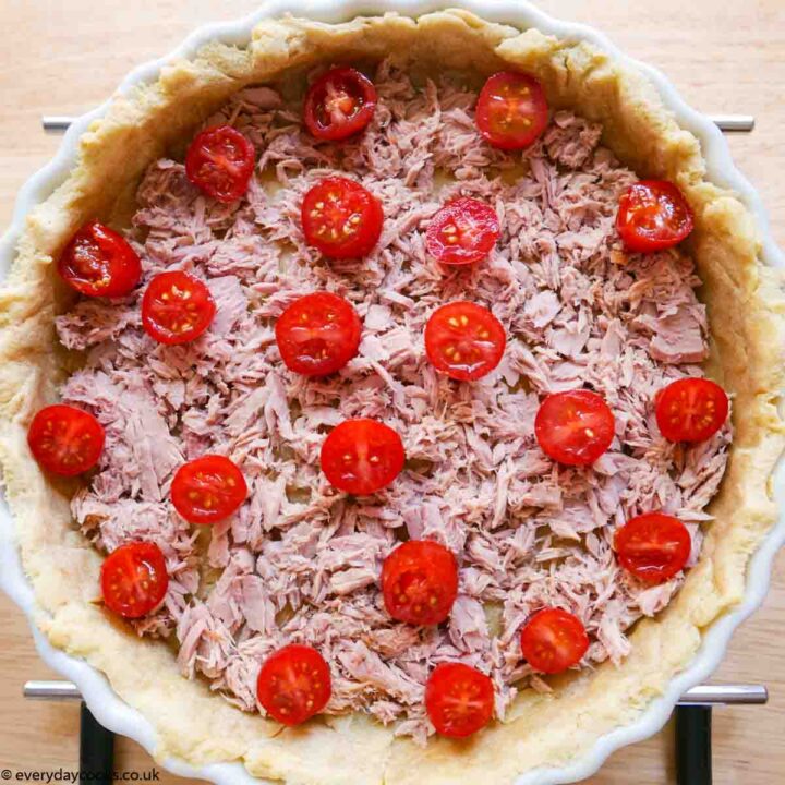 An pastry case with tuna and cherry tomatoes in a white china flan dish