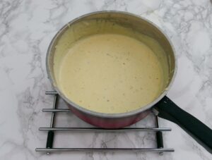 Cheese sauce in a red saucepan - ready to eat.