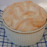 Black Forest Meringue Pudding viewed from above in a white souffle dish on a blue and white checked tea towel.