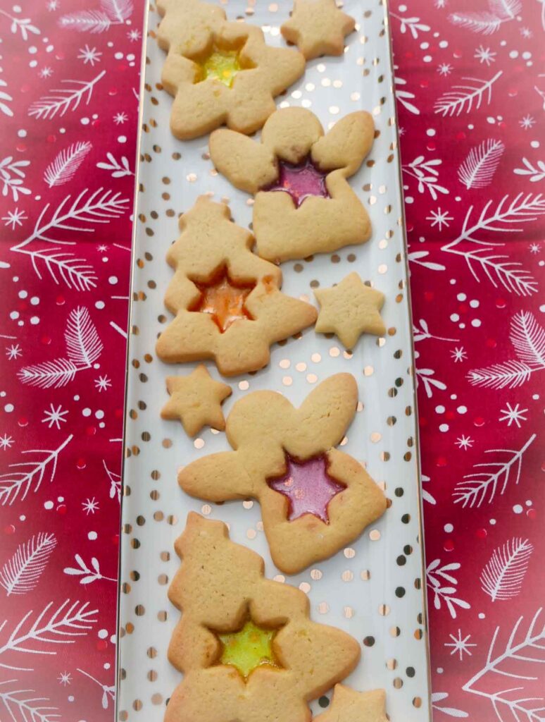 Stained glass biscuits. Angels and Christmas trees with star-shaped windows of orange, red and yellow