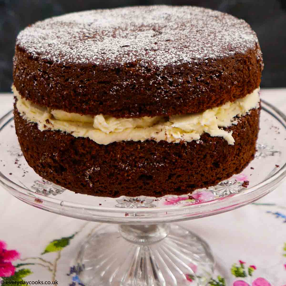 Large everyday chocolate cake on a glass cake stand