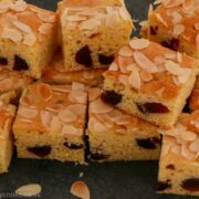 Squares of cherry and almond traybake on a slate