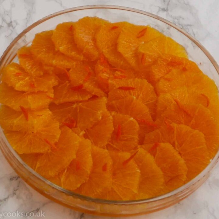 Oranges in Liqueur. Sliced oranges arranged in a shallow glass dish with slivers of orange peel decorating