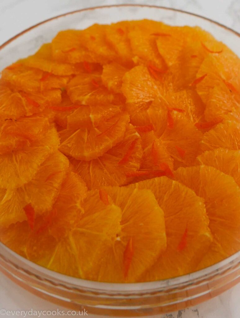 Oranges in Liqueur. Sliced oranges arranged in a shallow glass dish with slivers of orange peel decorating