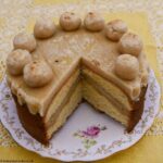 Orange Simnel Cake with a slice removed showing the layer of marzipan inside