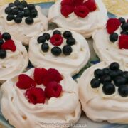 7 Pavlova nests, filled with cream, raspberries and blueberries, on a plate