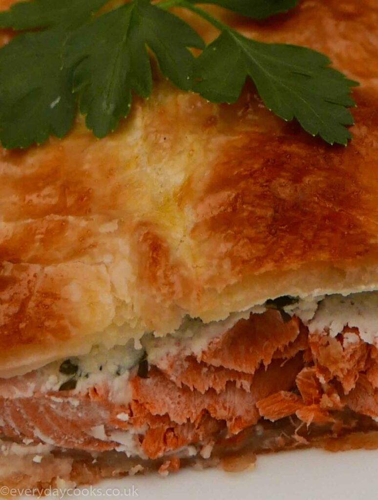 Salmon en Croûte - a slice of salmon baked in puff pastry with a parsley garnish.