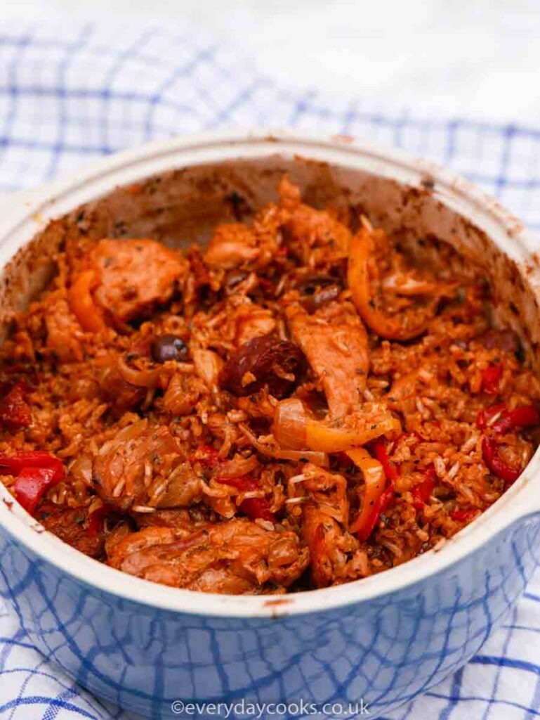 Spanish Chicken and Rice in a blue casserole dish on a blue checked tea towel