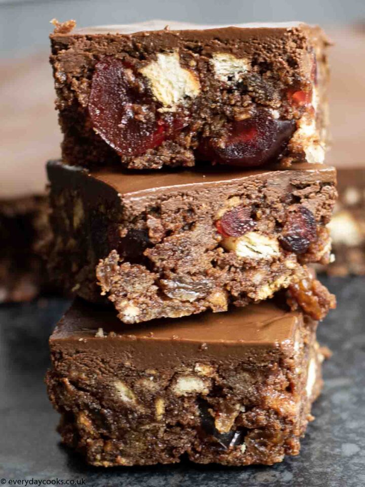 Slices of Chocolate Tiffin in a pile with the rest of the cake behind