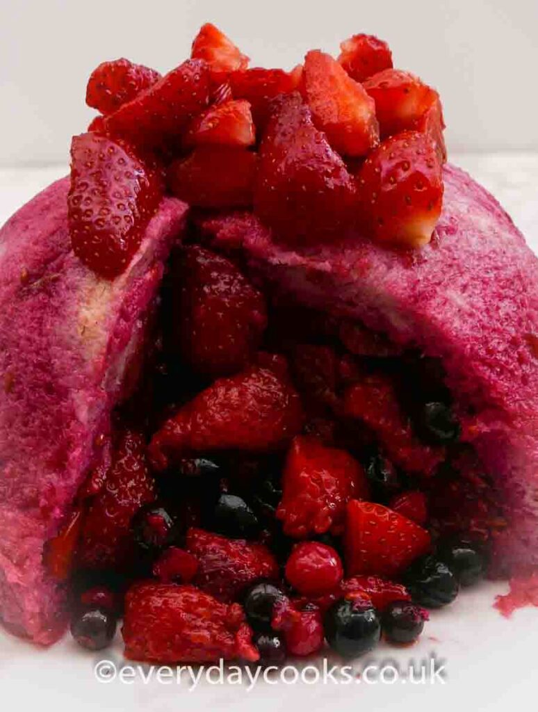 Summer Pudding full of berries with a slice taken.