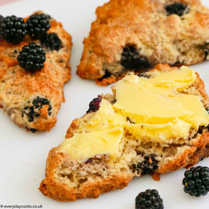 Buttered Blackberry Scones on a white plate with blackberries.