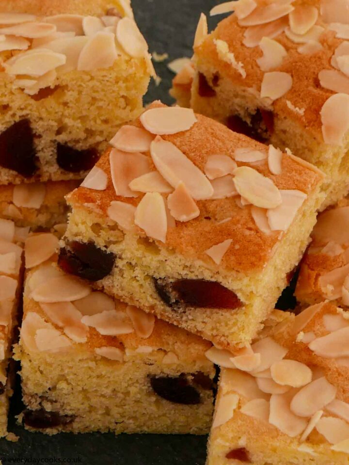 Squares of cherry and almond traybake on a slate