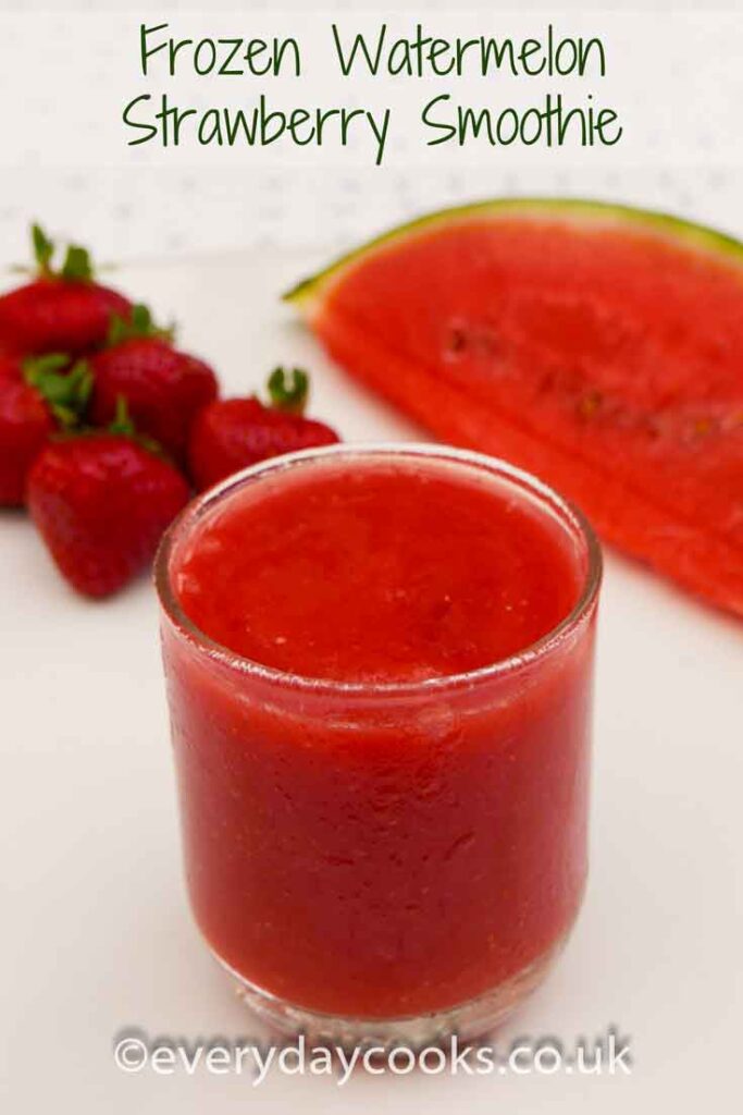 Frozen Watermelon Strawberry Smoothie in a short glass with a slice of watermelon and scattered strawberries.