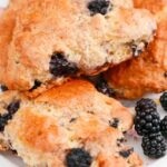 3 Blackberry Scones on a white plate with blackberries.