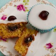 One whole and one cut Cherry Bakewell Cupcakes on a plate.