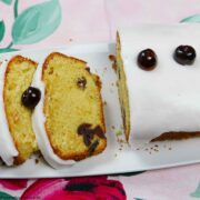 Torta di ciliegie ghiacciata con una fetta tagliata, su un piatto bianco.