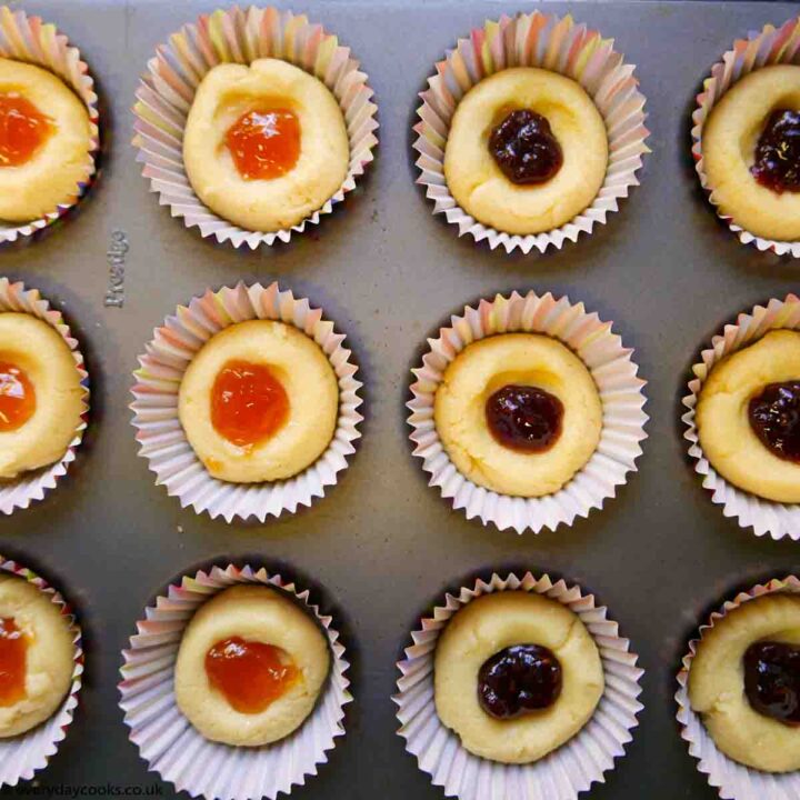 Uncooked hollowed-out, jam-filled Almond Meringue Buns in the tin