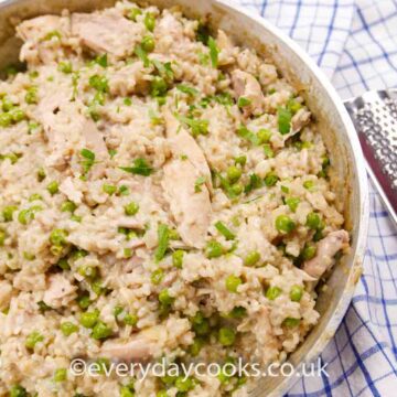 Chicken Risotto with peas in a large shallow pan on a blue checked cloth