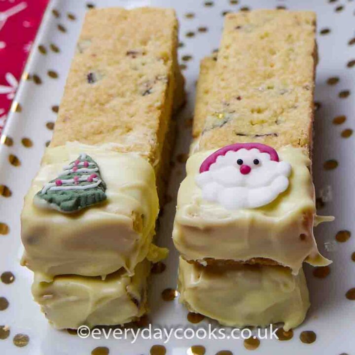 4 pieces of Christmas Shortbread part coated in white chocolate, on a china plate.