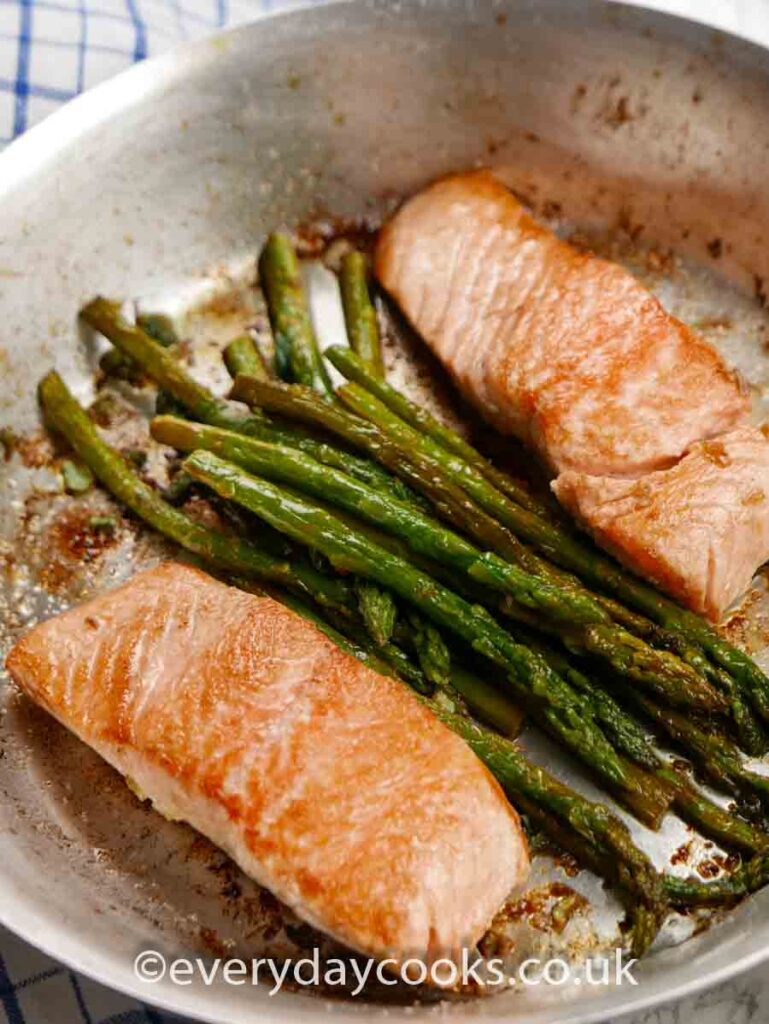 Pan-fried Lemon and Garlic Salmon with Asparagus in an aluminium frying pan.