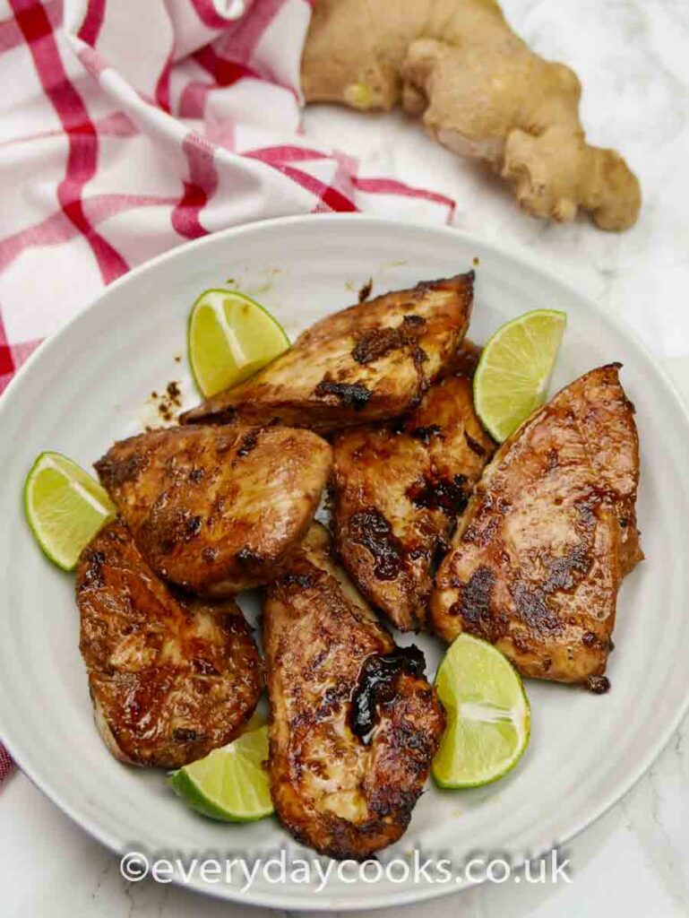 Pieces of Ginger Lime Chicken in a white dish with a quartered lime