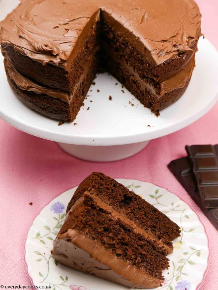 Easy Chocolate Fudge Cake on a white plate with a piece on a flowered plate