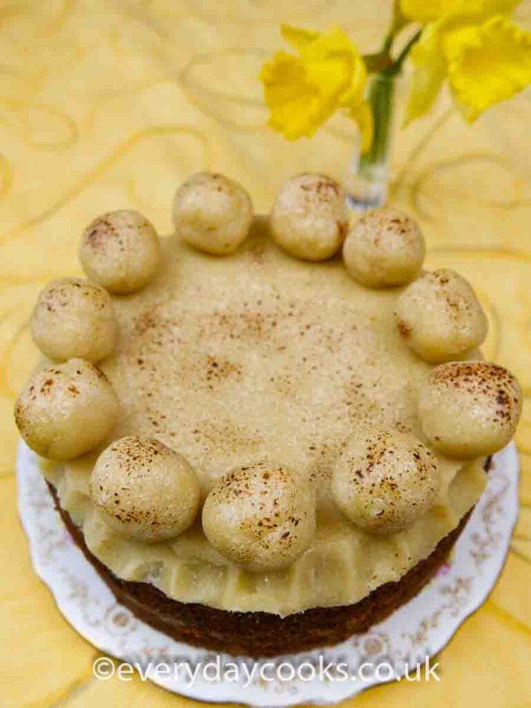 Light Simnel Cake on a patterned plate on a yellow cloth