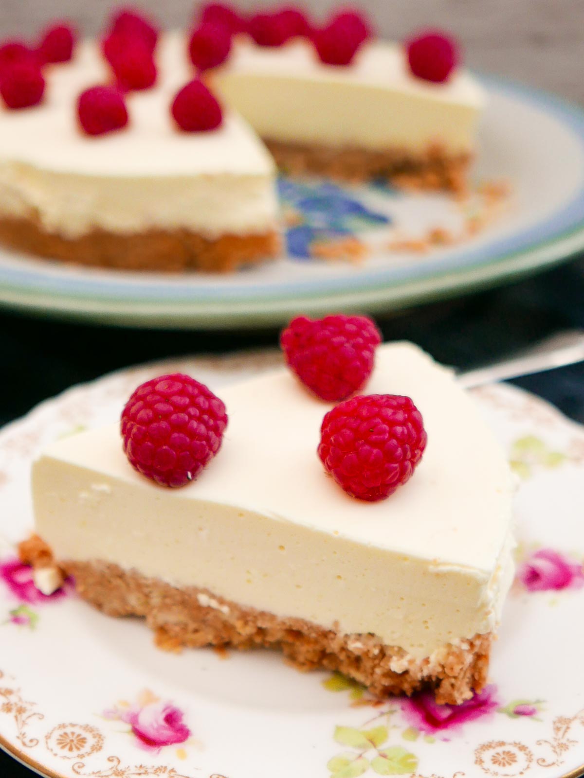 Slice of Easy Lemon Cheesecake with the rest of the cheesecake in the background.