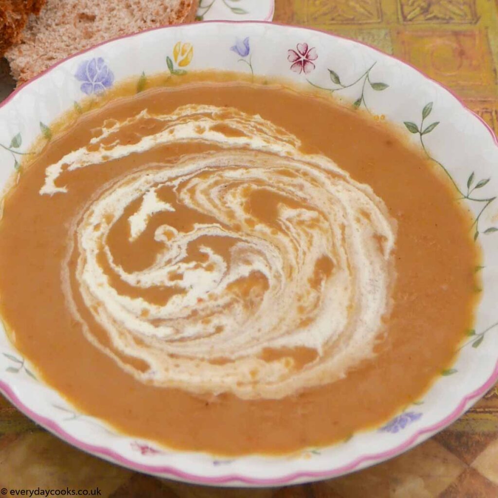 Christmas vegetable soup in a bowl with a piece of bread on a plate.