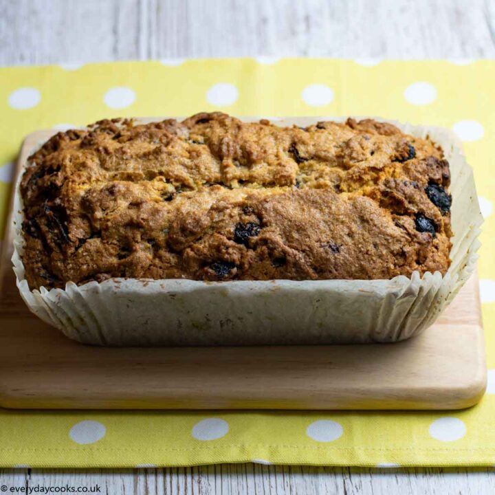 A Date and Walnut Loaf in a baking liner on a board.