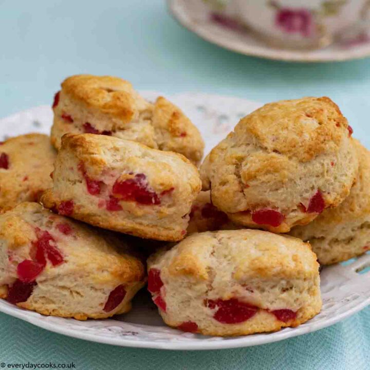 A plate of Cherry Scones with a teacup in the background on a blue cloth