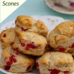 A plate of Cherry Scones with a teacup in the background on a blue cloth