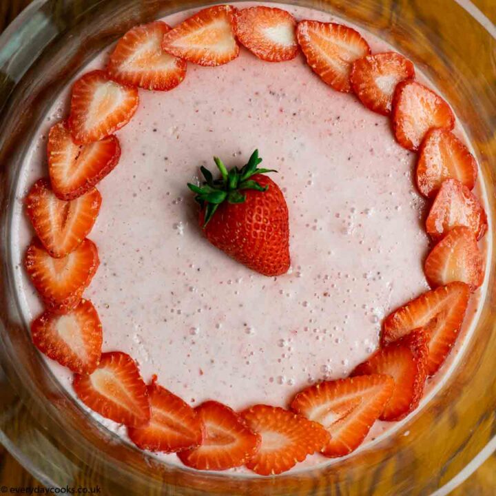 Easy Strawberry Mousse decorated with strawberry slices, in a glass bowl on a wooden table