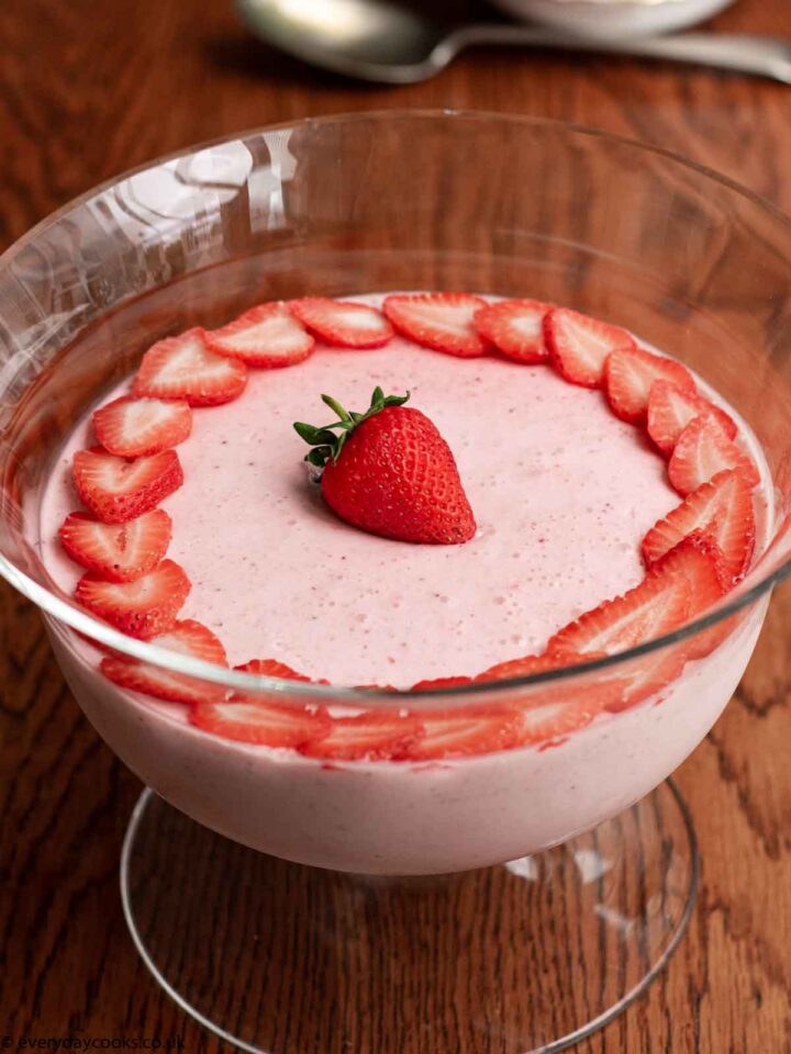 Easy Strawberry Mousse decorated with strawberry slices, in a glass bowl on a wooden table