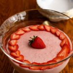 Easy Strawberry Mousse decorated with strawberry slices, in a glass bowl on a wooden table