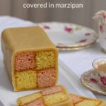 Easy Battenberg Cake on a white plate with 2 slices cut, with a cup of tea.