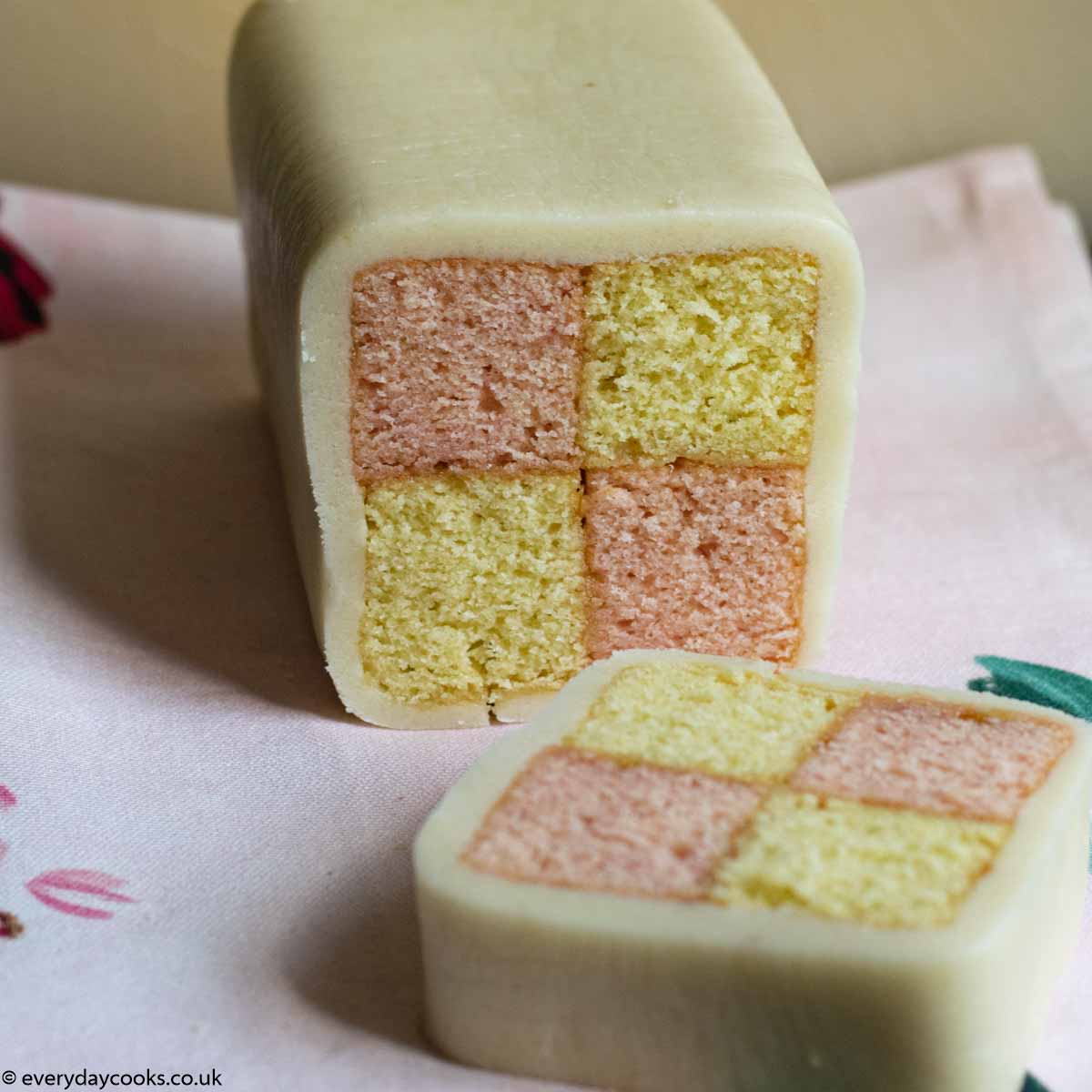 Easy Battenberg cake with a slice cut, on a pink cloth