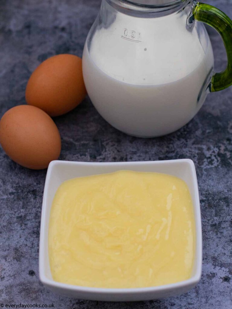 Bowl of homemade custard with 2 eggs and a jug of milk