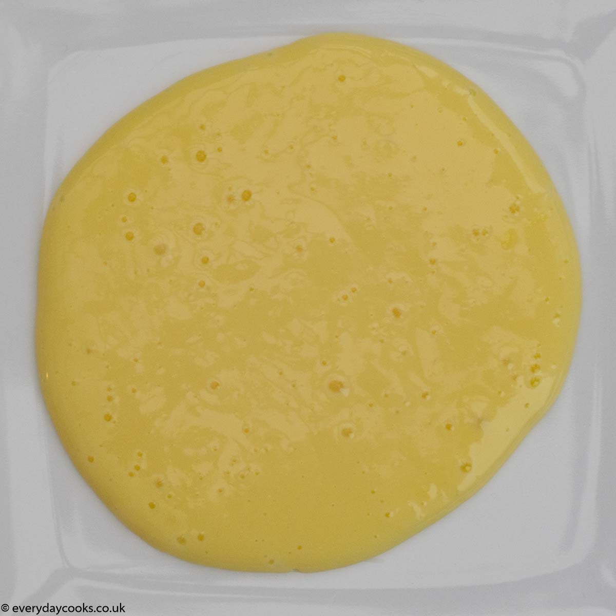 Custard whisked to remove the lumps, on a white plate