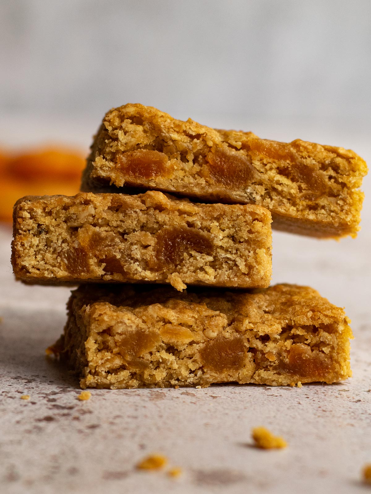 Stack of apricot oat bars with dried apricots in the background