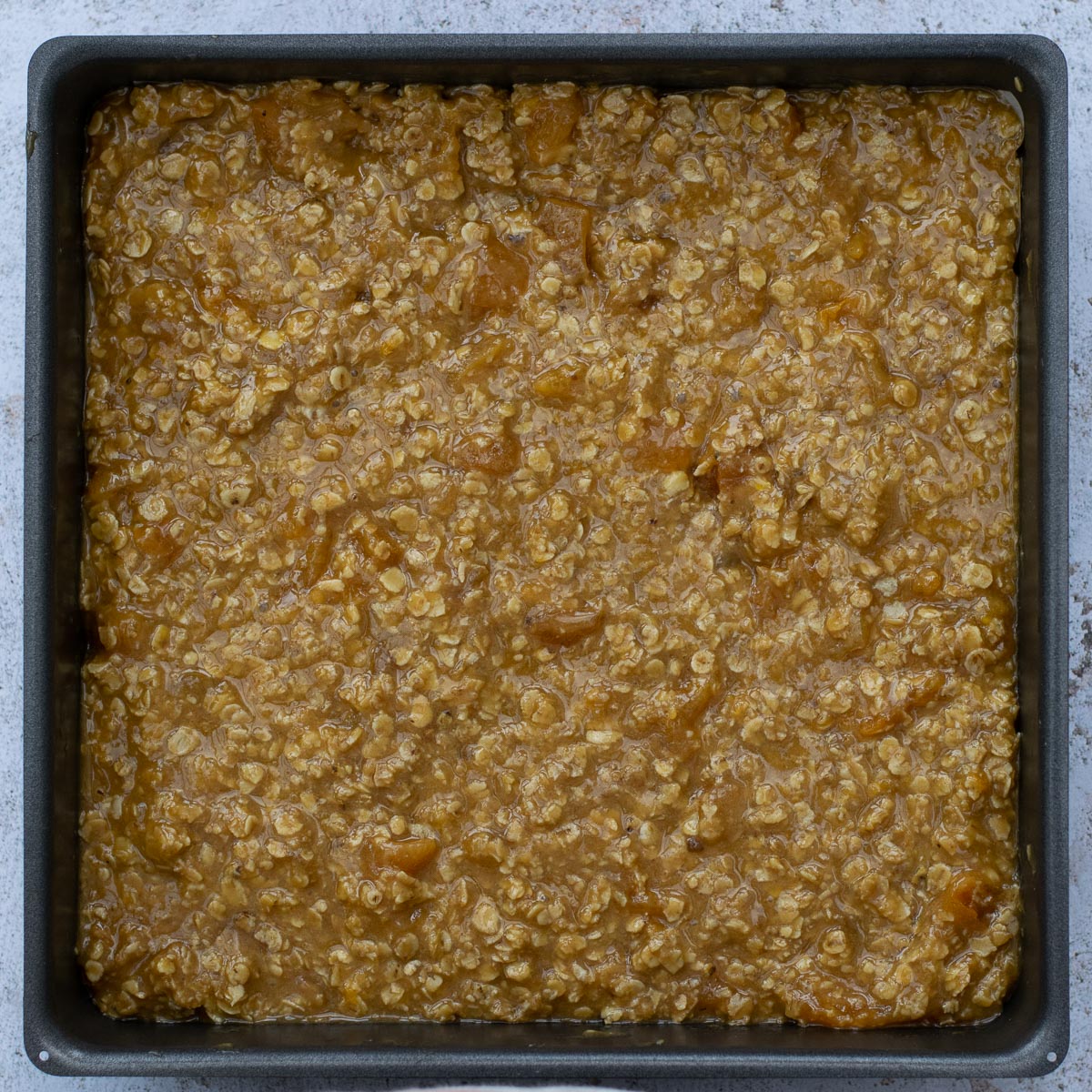 Baking tin of apricot oat bar mixture before cooking