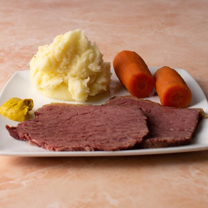 2 slices of Slow Cooker Salt Beef with carrots, mashed potato and mustard.