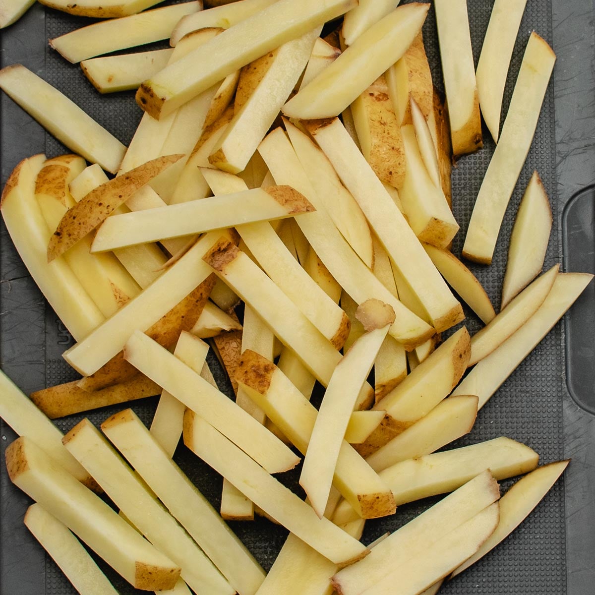 A pile of uncooked potato chips on a grey board