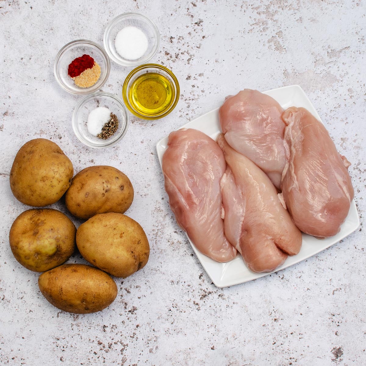 5 potatoes, 4 chicken breasts, dishes of olive oil and spices. Ingredients for Air Fryer Chicken and Chips